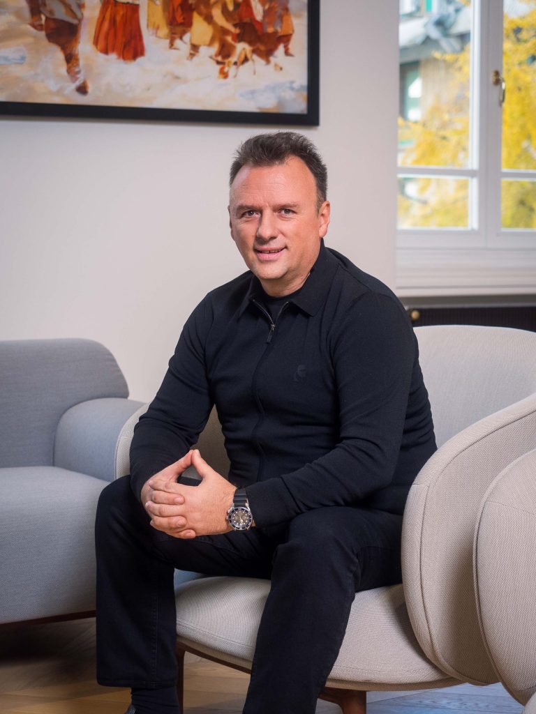 Profesionalno fotografisanje menadžmenta kompanije Inobacka u njihovim kancelarijama u Novom Sadu 2024. godine.  Na slici je muškarac u elegantnom crnom odelu, sedi u udobnom, bež nameštaju.  Ambijent je moderan i profesionalan, sa neutralnim bojama i kvalitetnim detaljima.  Fotografija je oštra i jasna, sa dobrim osvetljenjem, što čini sliku atraktivnom i profesionalnom.  Ovo je primer korporativnog fotografisanja koje ističe profesionalnost i uspešnost kompanije Inobacka.