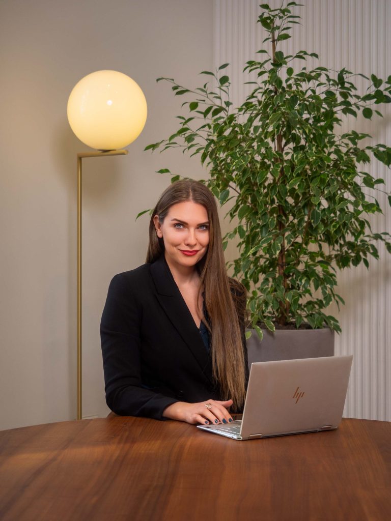 Profesionalno fotografisanje menadžmenta kompanije Inobacka u njihovim kancelarijama u Novom Sadu.  Žena u elegantnom crnom sakoou sedi za stolom i radi na laptopu.  Svetle kancelarije, moderno nameštaj i lepa sobna biljka stvaraju profesionalnu i ugodnu atmosferu.  Fotografije su savršene za predstavljanje kompanije i njenog tima.